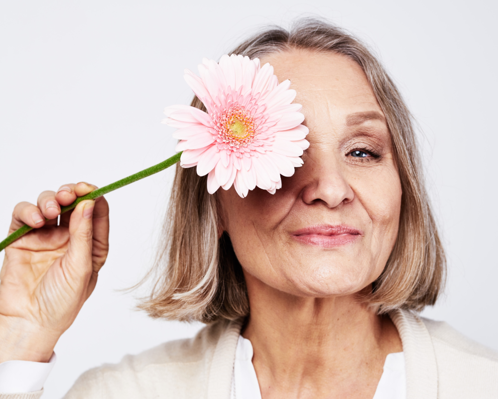 Mujer mayor con flor rosada en el ojo