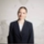 Mujer con blazer negro sobre fondo neutro