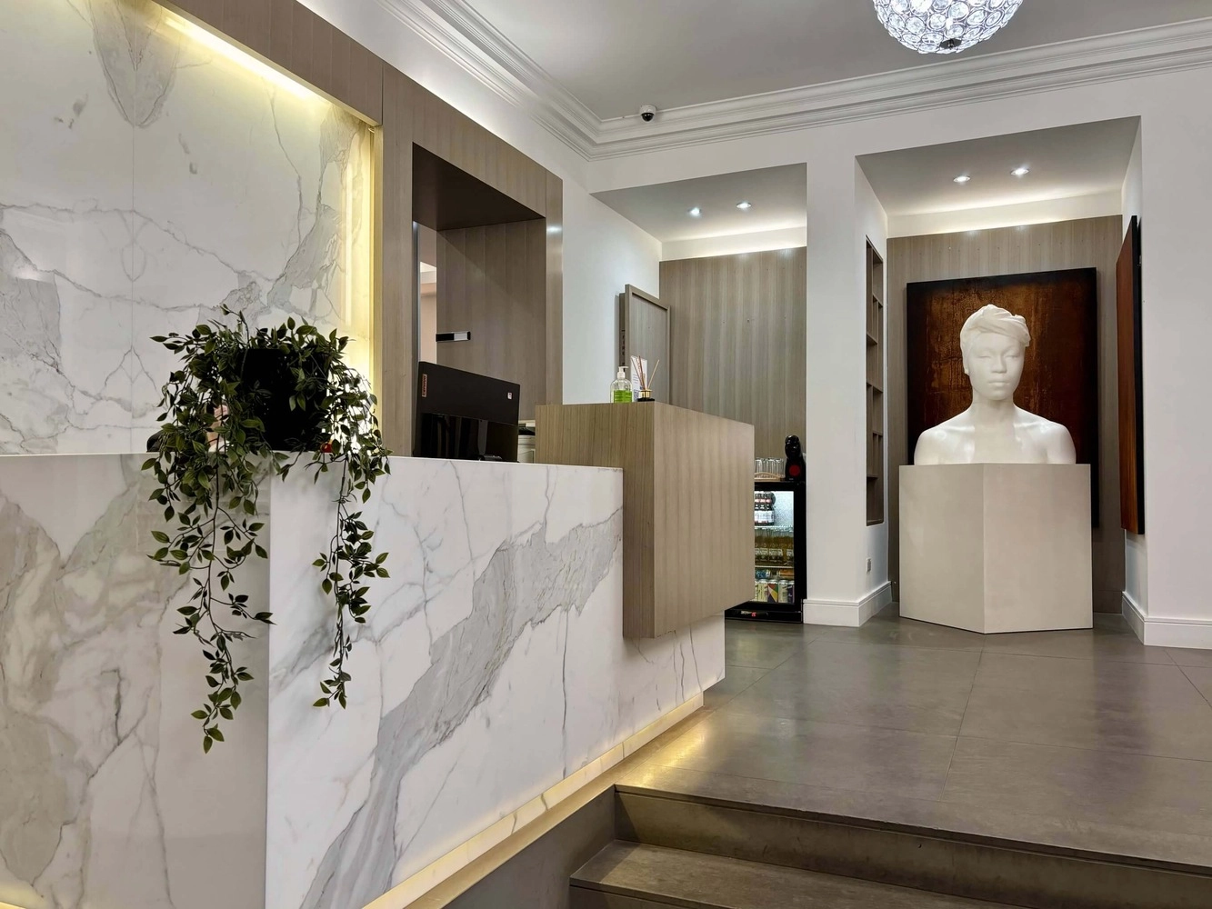 Recepción moderna con mostrador de mármol y escultura