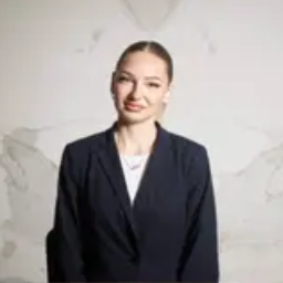 Mujer sonriente con blazer oscuro sobre fondo claro