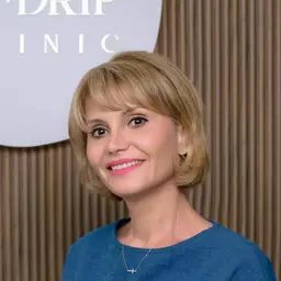 Mujer sonriente con pelo corto rubio y blusa azul